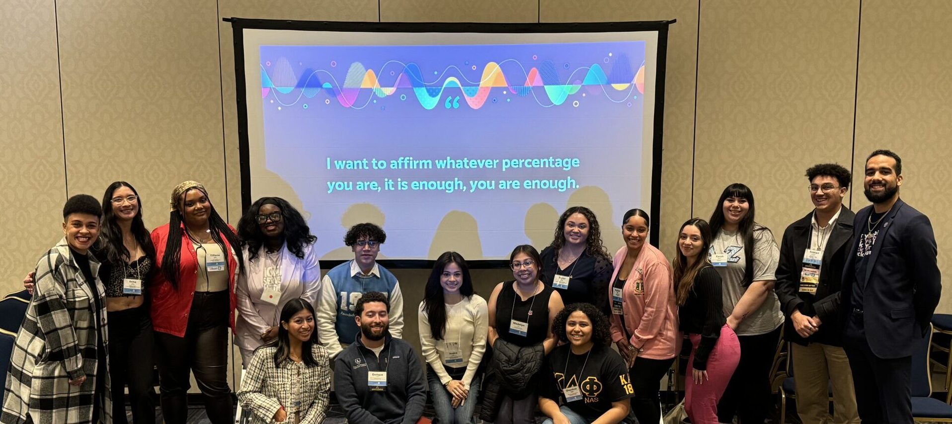 Christina posing with a group of 15 clients at the Northeast Greek Leadership Association conference. The group is racially diverse and includes adults as well as collegiate students.